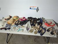 Overview of the lot showing a collection of women's shoes, hats, and costume jewelry arranged on a table.