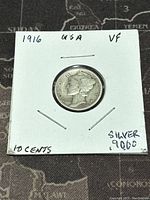 Obverse side of the 1916 US Mercury Dime coin showing the Winged Liberty Head in very fine condition held in a cardboard flip with notes.