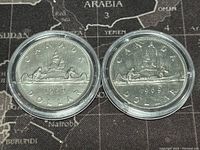 Reverse sides of the 1968 and 1969 Canadian dollar coins showing canoe scene design.