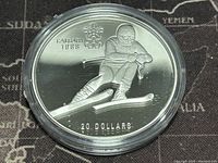 Reverse side of the silver proof coin showing skiing athlete, Calgary 1988 text, Olympic rings, and denomination