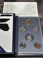 Specimen coin set in blue foam insert with protective case and accompanying specifications sheet.