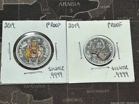 Obverse and reverse sides of the 50 cent and 25 cent Canadian silver coins from 2019. Coins are in protective holders with handwritten notes indicating silver purity and proof condition.