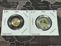 Two Canadian Twoonie coins in holders, 2022 and 2023, showing reverse sides. The 2023 coin features color artwork with a bird and floral design. The 2022 coin shows the standard reverse design.