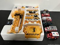 Overview of large yellow construction crane toy and small vehicles arranged in styrofoam packaging