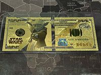 Front side of gold foil Star Wars $100 banknote featuring Yoda and detailed gold embossing.