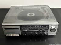 Front view of the stereo cassette receiver featuring AM/FM dial, cassette controls, and tuning knob with visible crack on front panel.