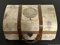 Front view of the closed small decorative storage box with dome-shaped lid showing globe and vintage text design, faux leather straps and latch.