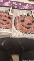 Photo showing two unopened Halloween craft kits with a pixelated orange jack-o'-lantern design on the packaging.