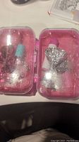 Two pink translucent plastic self care kits with small bottles and silver glitter bows inside.