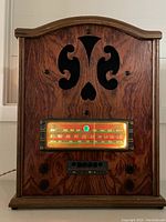 Front view of the antique wooden cabinet radio showing decorative cut-out pattern and illuminated dial.