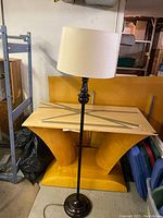 Full view of the vintage floor lamp showing the beige fabric lampshade and dark brown slender stand against a background of furniture pieces.