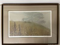Straight-on photo of the entire framed print showing frame, mats, glass, and full composition of grasses, tree, hunter and dog.