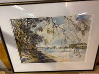 Framed watercolour landscape showing trees, promenade, sailboats on water.