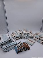 Photo of seven folded towels including bath towels and smaller towels, all with a striped pattern in beige, blue and brown hues.