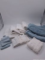 Photo showing multiple white and blue towels folded and stacked showing different sizes and textures