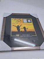 Front view of the frame showing the size label and two sample images inside the frame, still with white corner guards to protect the frame edges.