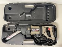 Top view of Porter Cable Tiger Saw in a molded plastic carrying case with the blade and power cord visible.