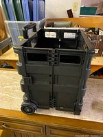 Black collapsible cart in upright position showing handles and wheels