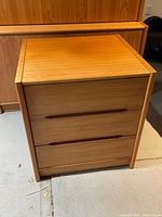Frontal view of teak end table showing two drawers with recessed handles