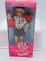 Front view of the boxed 1994 Walt Disney World Barbie in pink box showing doll with silver jacket, holding red Mickey balloon and red purse.