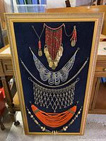Full view of wooden gilt frame with black felt backing displaying five vintage necklaces