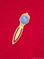 Close-up front view of vintage Wedgewood style page saver with blue ceramic horse medallion inset in gold-tone metal.