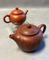 Two miniature Chinese teapots shown together, one plain and one carved