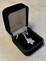 Jewelry box holding the silver chain with Hamsa hand pendant visible.