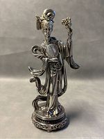 Front view of the silver Asian woman statue showing detailed facial features, costume, fan, and flower.