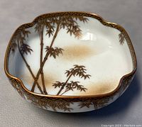 Side angle showing bamboo painted design and scalloped edges with gold trim.