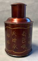 Front view of the Asian metal decanter showing etched Chinese characters on reddish-brown surface with gold accents.
