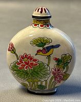Photo of the snuff bottle showing bird and flower enamel painting on one side against a neutral background