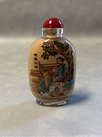 Front view of the Chinese reversed painted glass snuff bottle showing two traditional Chinese figures and Chinese characters with a tree in the background.
