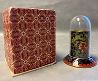 Photo showing the cloisonné toothpick holder with its decorative red patterned box beside it.