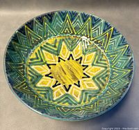Side angled view of the round handmade pottery plate/bowl showing pattern and form.