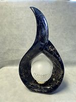 Front view of the sculptural MCM lamp with black marble-like frame and frosted glass globe.