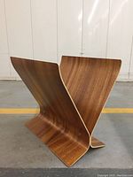 Multiple angles of a mid-century modern magazine rack made from bent teak wood showing the V-shaped curved structure and medium brown wood grain finish.
