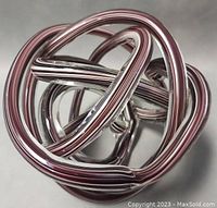 Top angled view emphasizing intertwined loops and striped pattern in glass sculpture