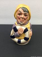 Photo showing a Royal Doulton miniature Toby mug with a character wearing a yellow hat and coat, holding a blue and white life preserver.