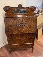 Front view of antique ornate secretariat cabinet showing drop front desk and mirror on upper panel.