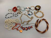 Photo showing different assorted costume jewelry including necklaces and bangles arranged on a white background