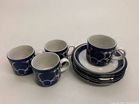 Four blue and white hand-painted espresso coffee mugs, each with an abstract floral design and a small handle.