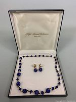 Full view of the necklace and clip-on earrings inside the box with silk lining