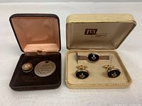 Photo of two presentation cases containing Independent Order of Odd Fellows items on the left and Masonic cufflinks and tie bar set on the right