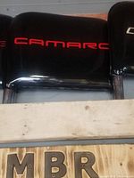 Close-up image of the black Camaro seat back showing the red embroidered 'CAMARO' text and chrome frame underneath.