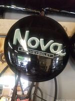 Front view of round black vinyl seat cushion with white 'Nova by Chevrolet' logo