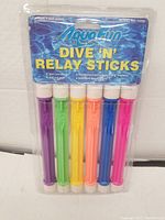 Front view of AquaFin Dive 'N' Relay Sticks blister packaging showing six colorful sticks in purple, green, yellow, orange, blue, and pink.