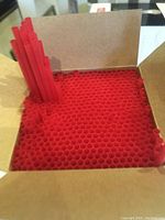 Top view of red plastic straws tightly packed inside an open cardboard box, showing the honeycomb-like arrangement of straws.