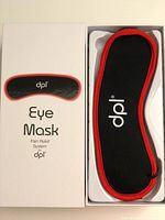 Photo of the new dpl Eye Mask Pain Relief System in white retail box and mask inside the box. Black eye mask with red edge trim, branded with dpl logo.