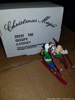 Photo showing the Goofy skiing Christmas Magic collectible ornament with its original box labeled 'Christmas Magic Goofy Disney'.